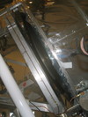 An edge-on view of the mirror.  The shiny part on top right is the scoop.  To the bottom left is one of the aluminum box beams which make up the inner frame.  Along this runs a copper pipe that's used for the fluid balance system.  The curved part between these is the back surface of the mirror.  From this, a couple of struts extend to the triangular mounting plate which secures the mirror to the inner frame.